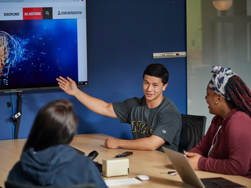 Student gesturing to a smart board that has a picture of a broken lightbulb on it.