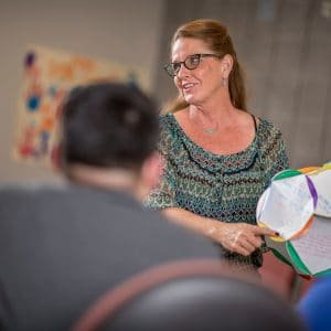 E L E M meeting with woman holding up craft made by group.