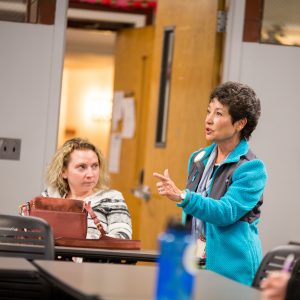 Woman addressing classroom.