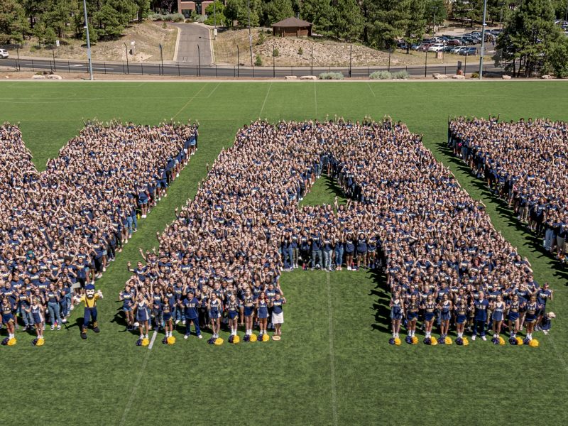 N A U students form the N AU logo on a field.
