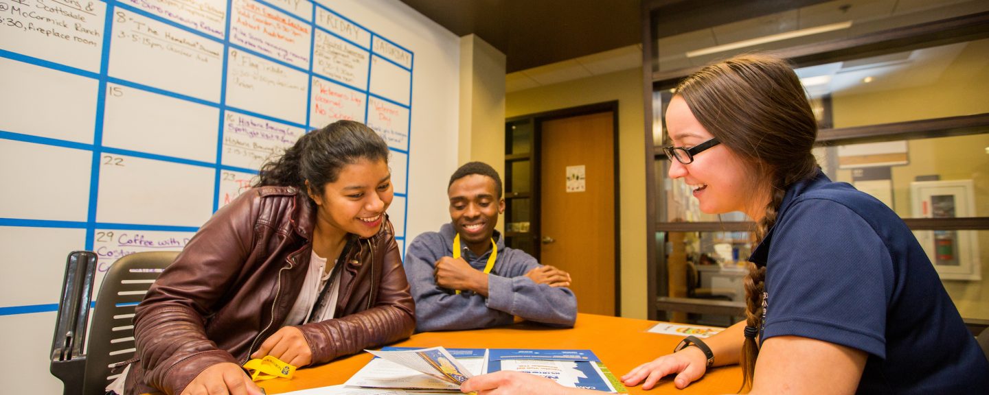 Students review a book together.