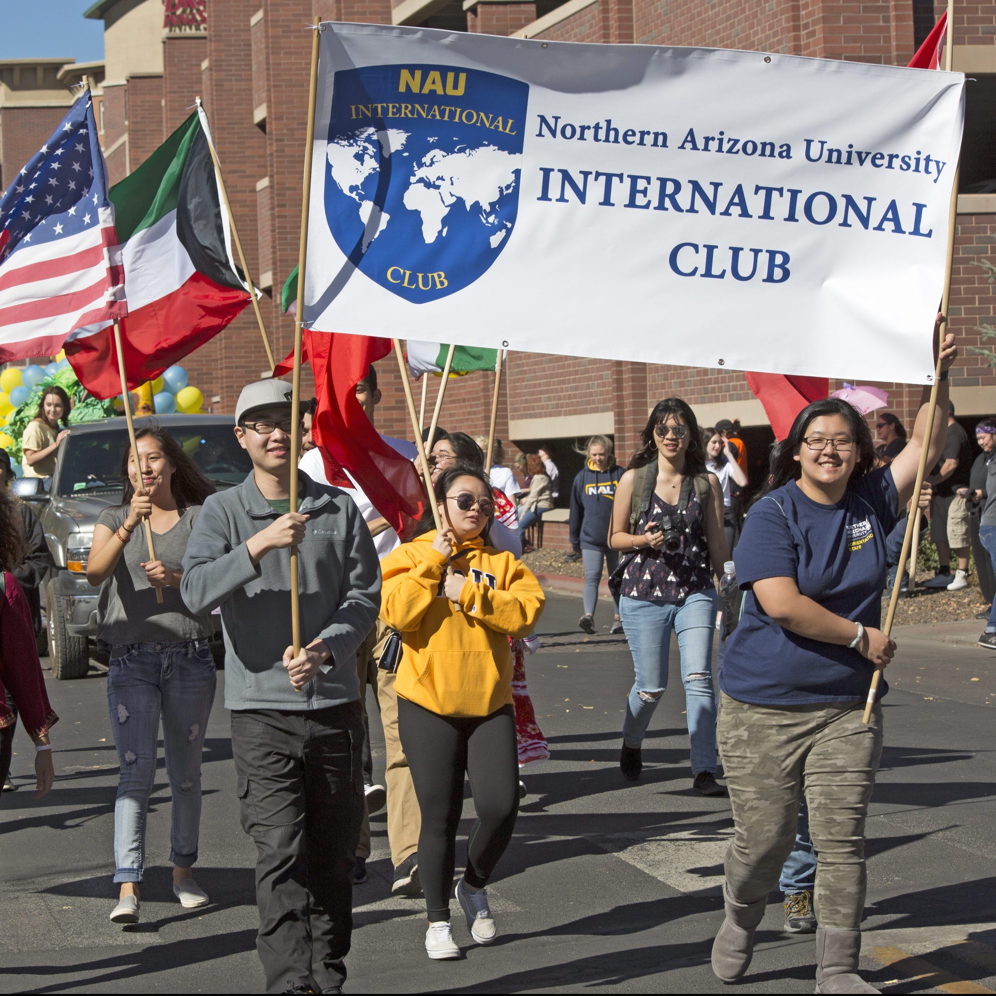 Students smiling while holding the International Club banner.