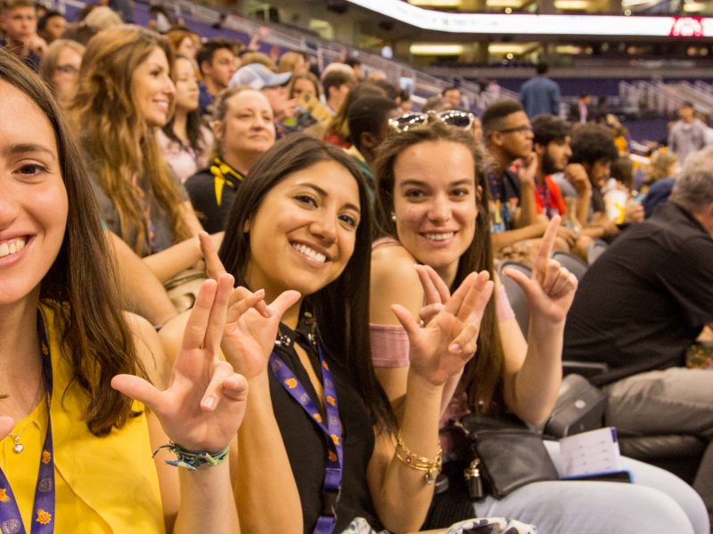Students smiling while throwing up their LJs.