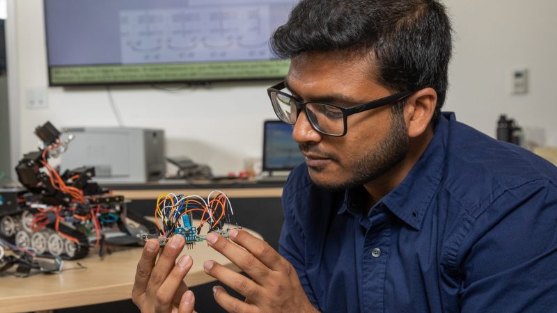 A student holding a part of a machine.