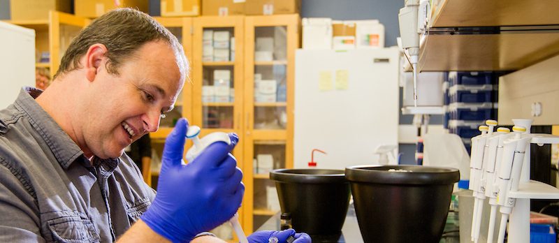 A student holding a syringe in a lab.