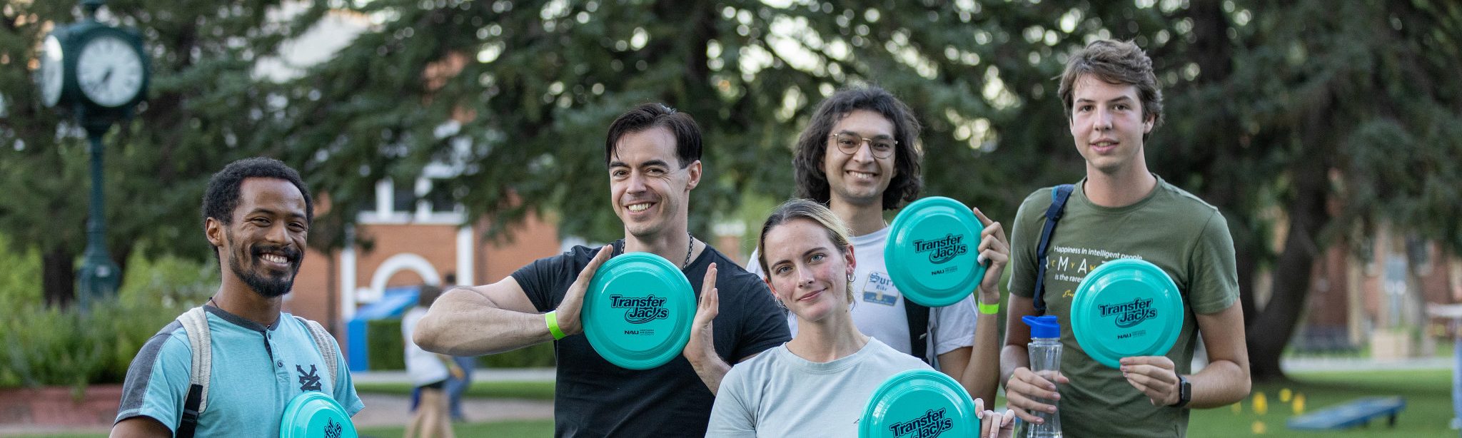 Students holding up teal frisbees outside.