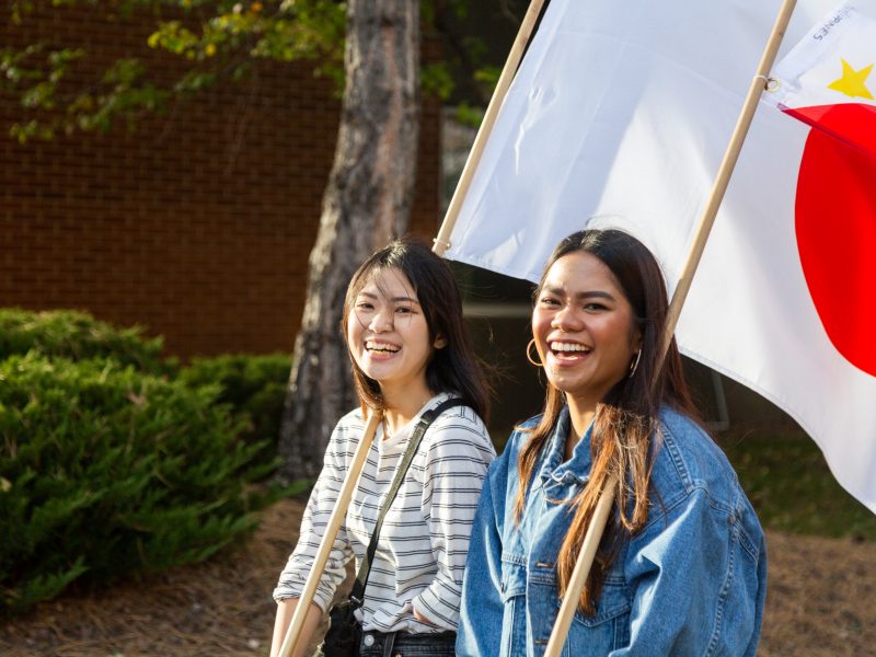 Two students walking with flags.