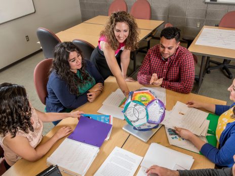 Teacher pointing at a model surrounded by students