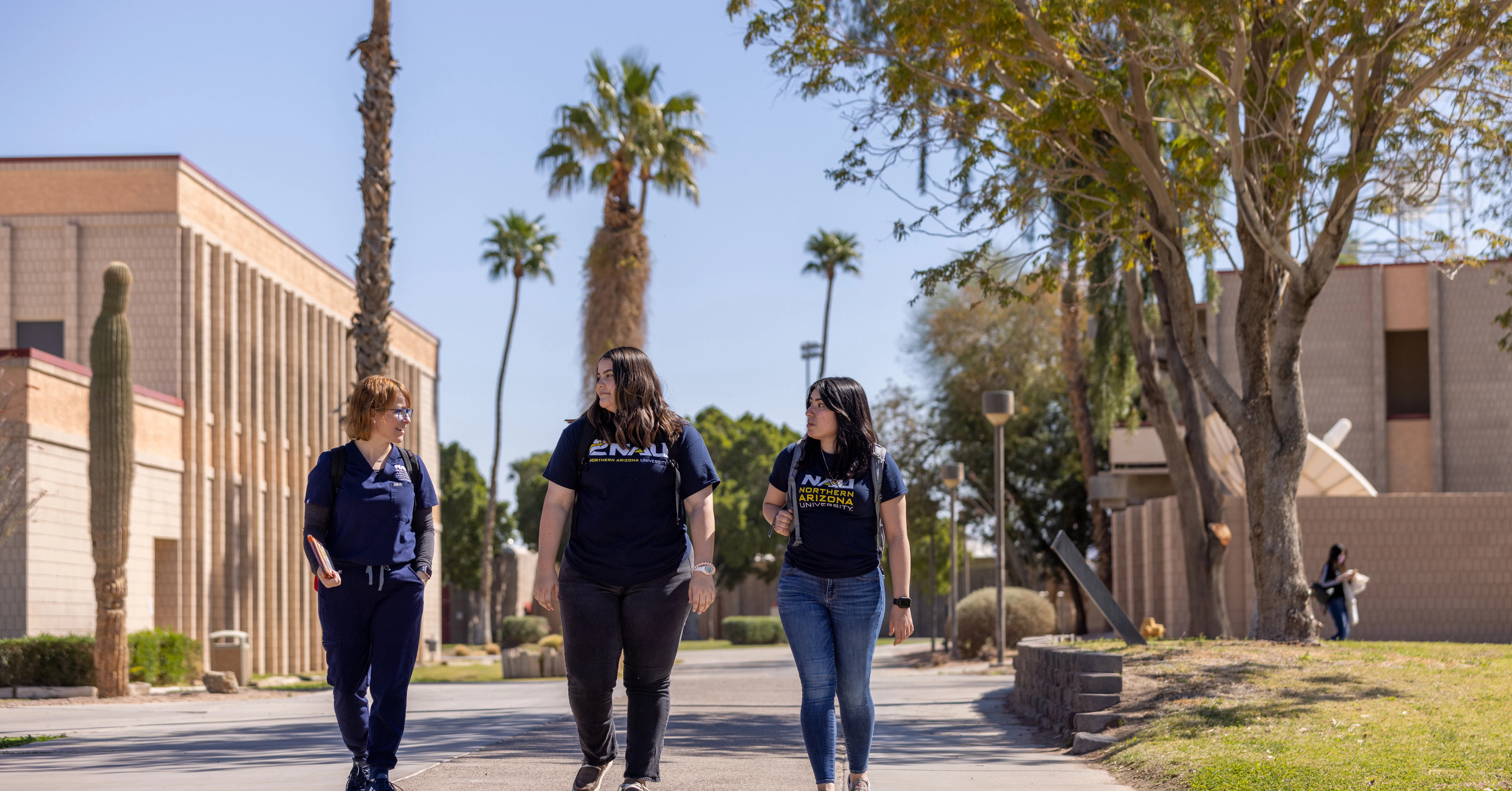Three individuals walking on campus.
