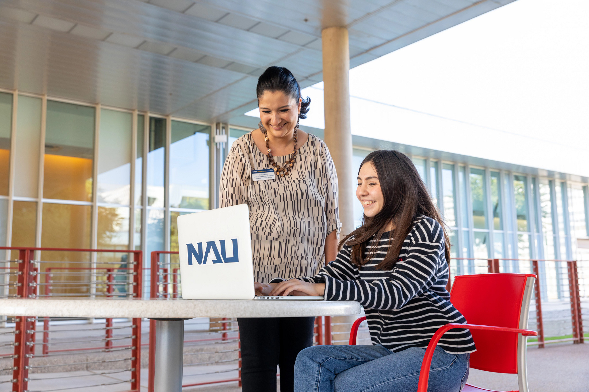 N A U&ndash;Yuma advisor works with a student on their laptop outside.