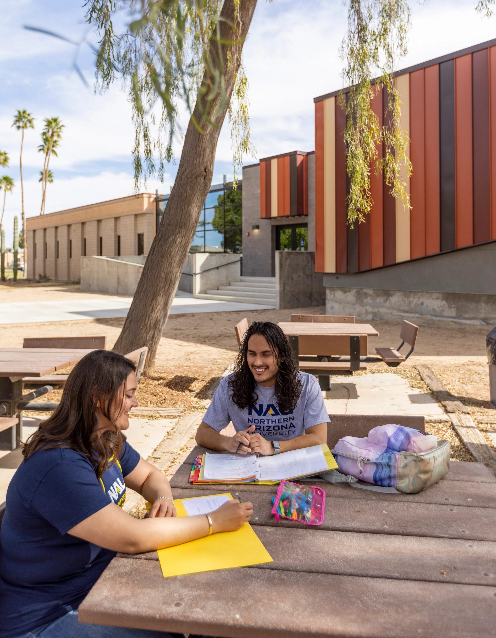 Two N A U&ndash;Yuma students sitting outside.
