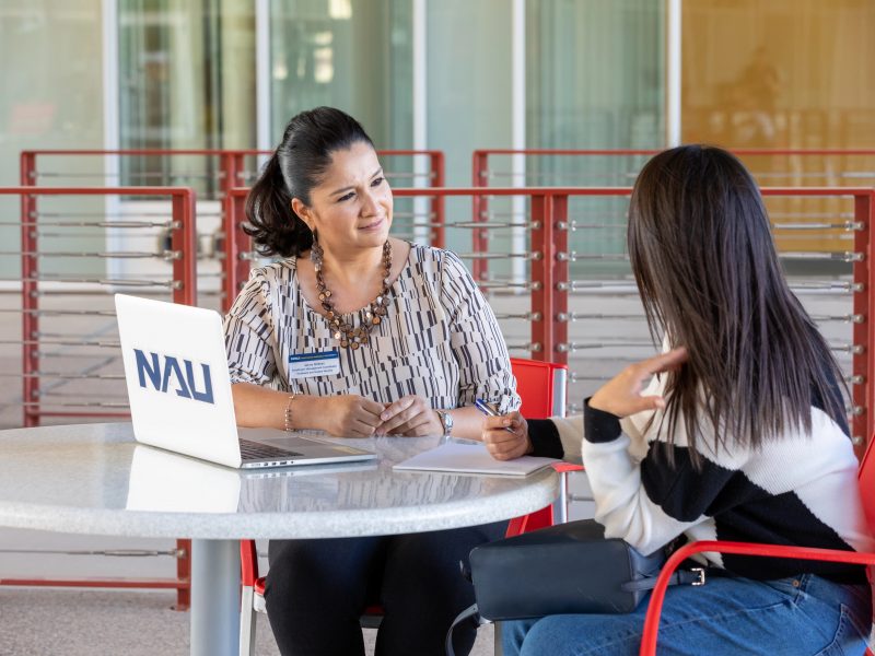 An N A U&ndash;Yuma advisor working with a student outside.
