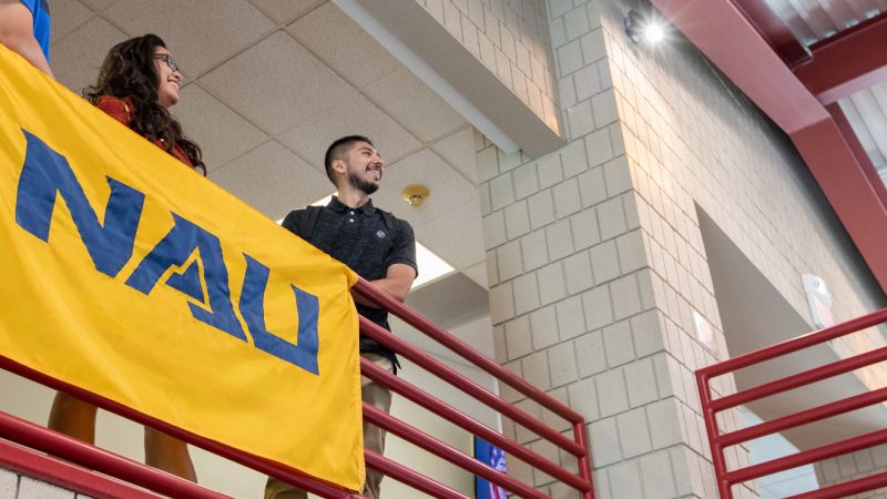 Students standing and smiling next to a N A U&ndash;Yuma banner.