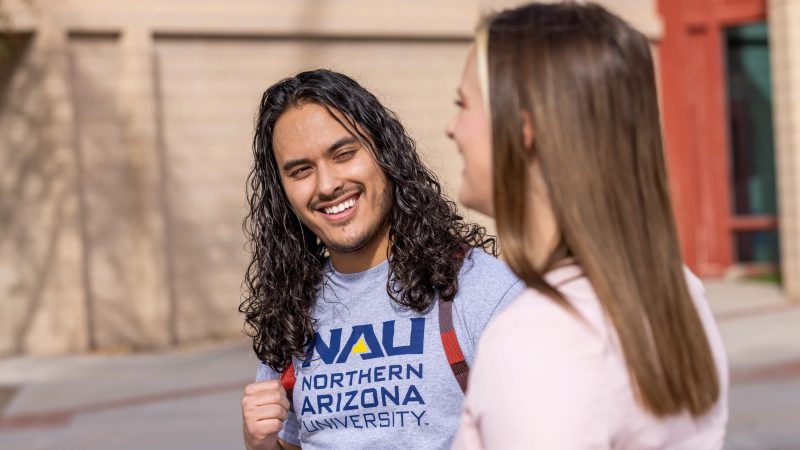 Students smile while talking outside.