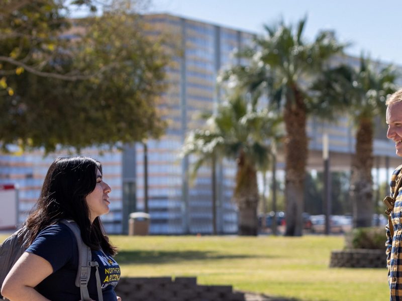 Two N A U&ndash;Yuma students standing outside.