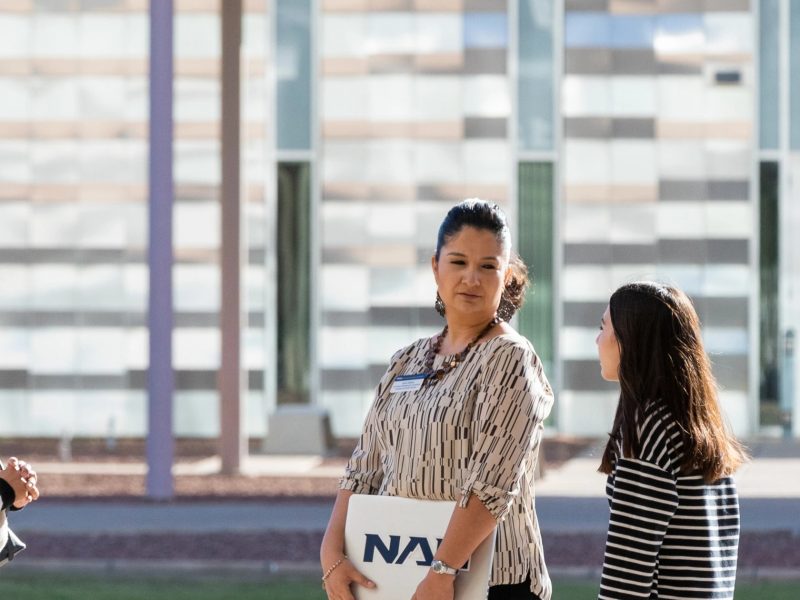 Students talking with an advisor outside at the N A U&ndash;Yuma campus.
