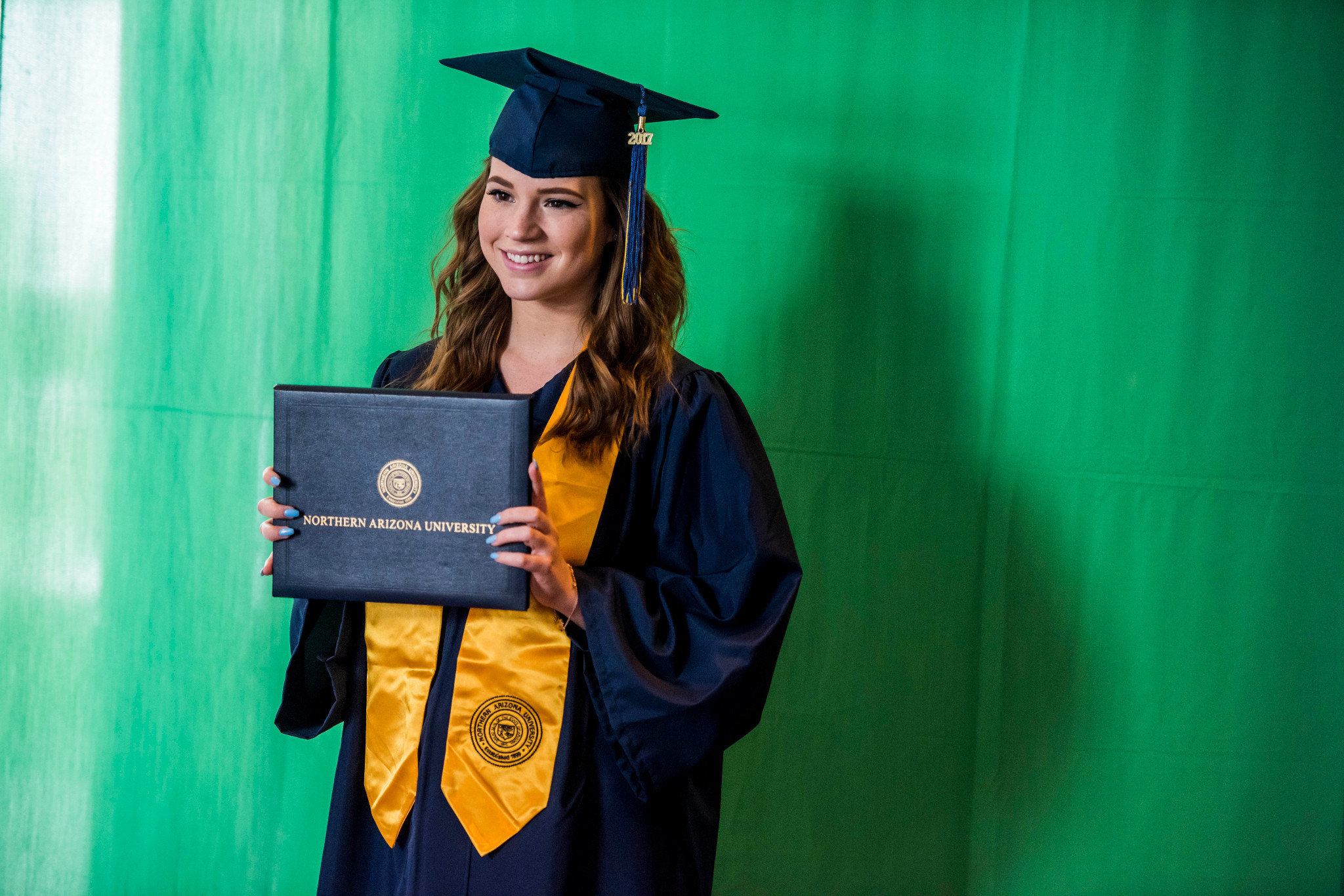 A student at N A U&ndash;Yuma holding up their diploma.