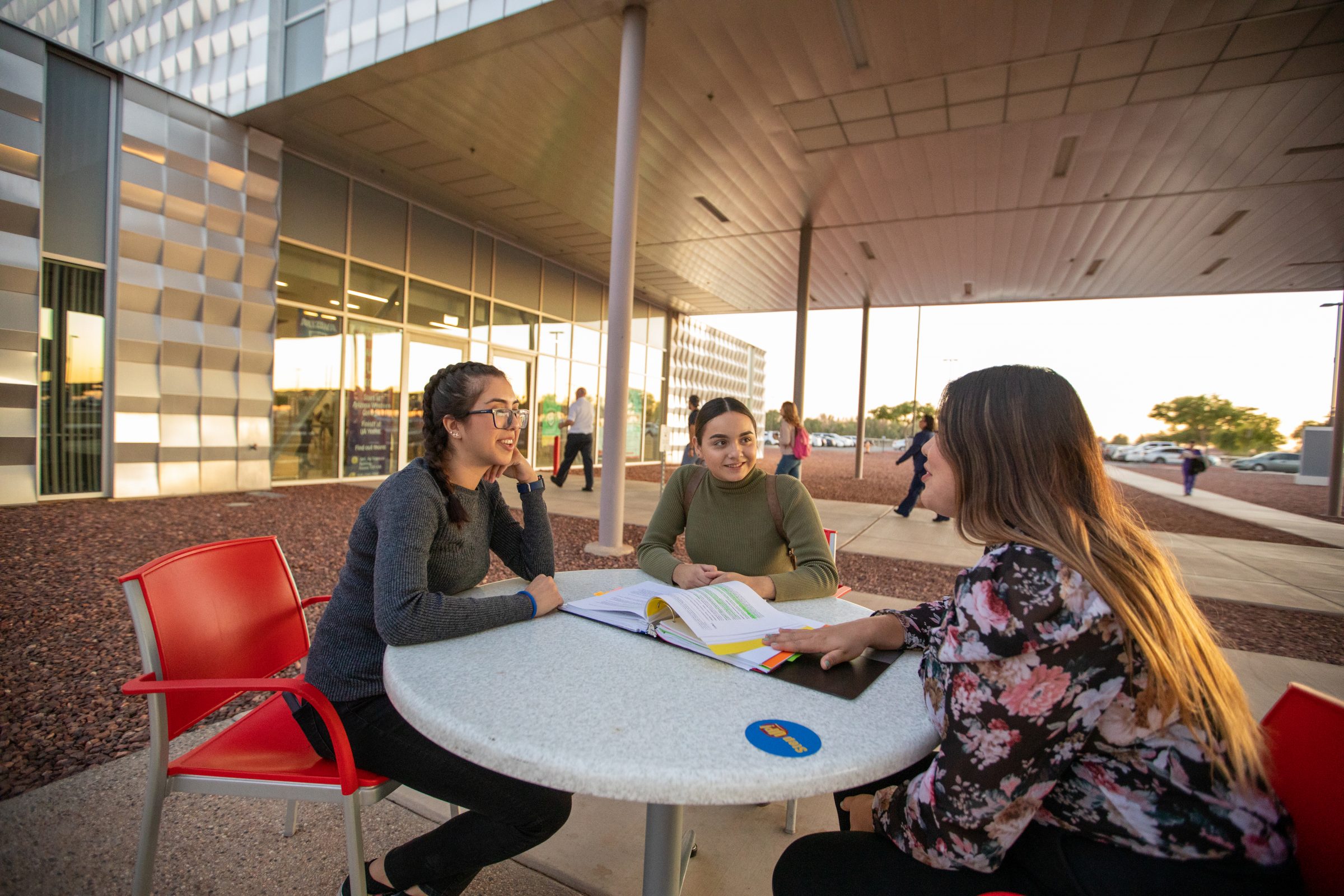 Three students sitting at a table on campus.