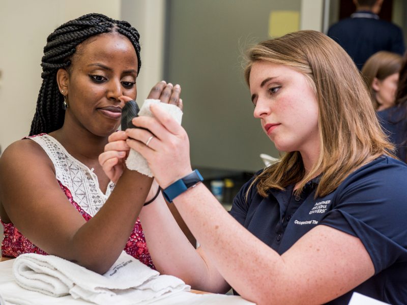 Student wrapping patient with bandage.