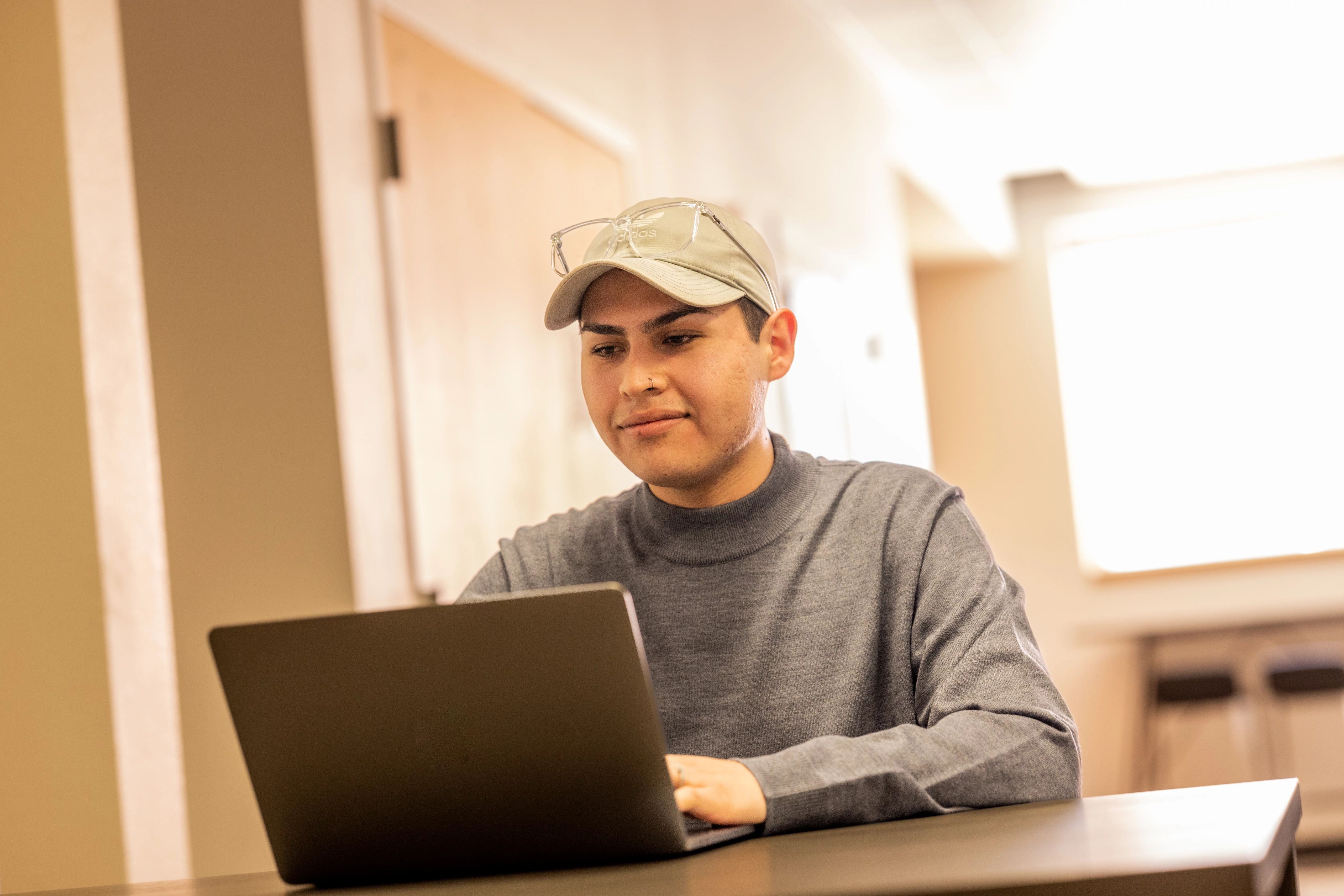 Student working on laptop smiling.