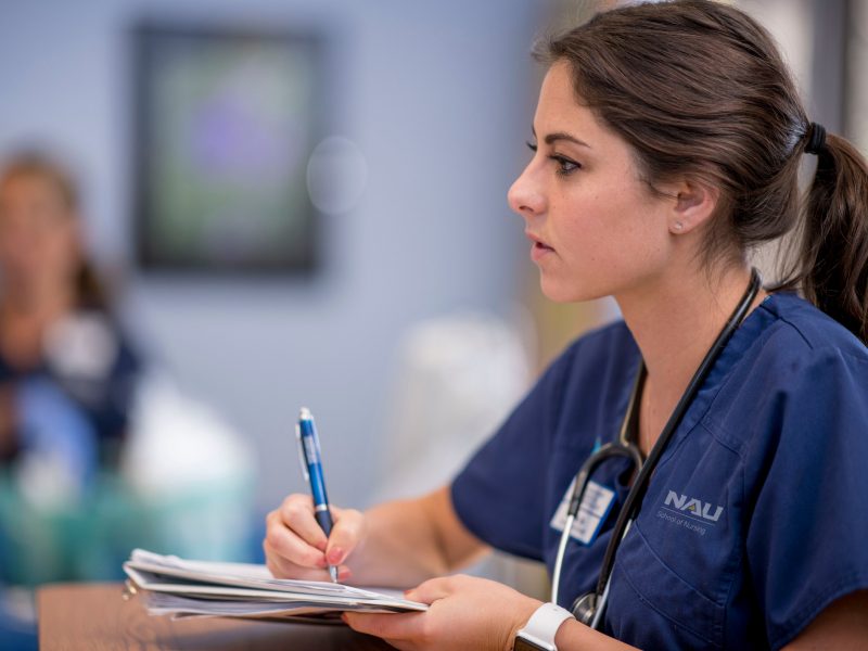 A student in the N A U nursing program takes notes in class.