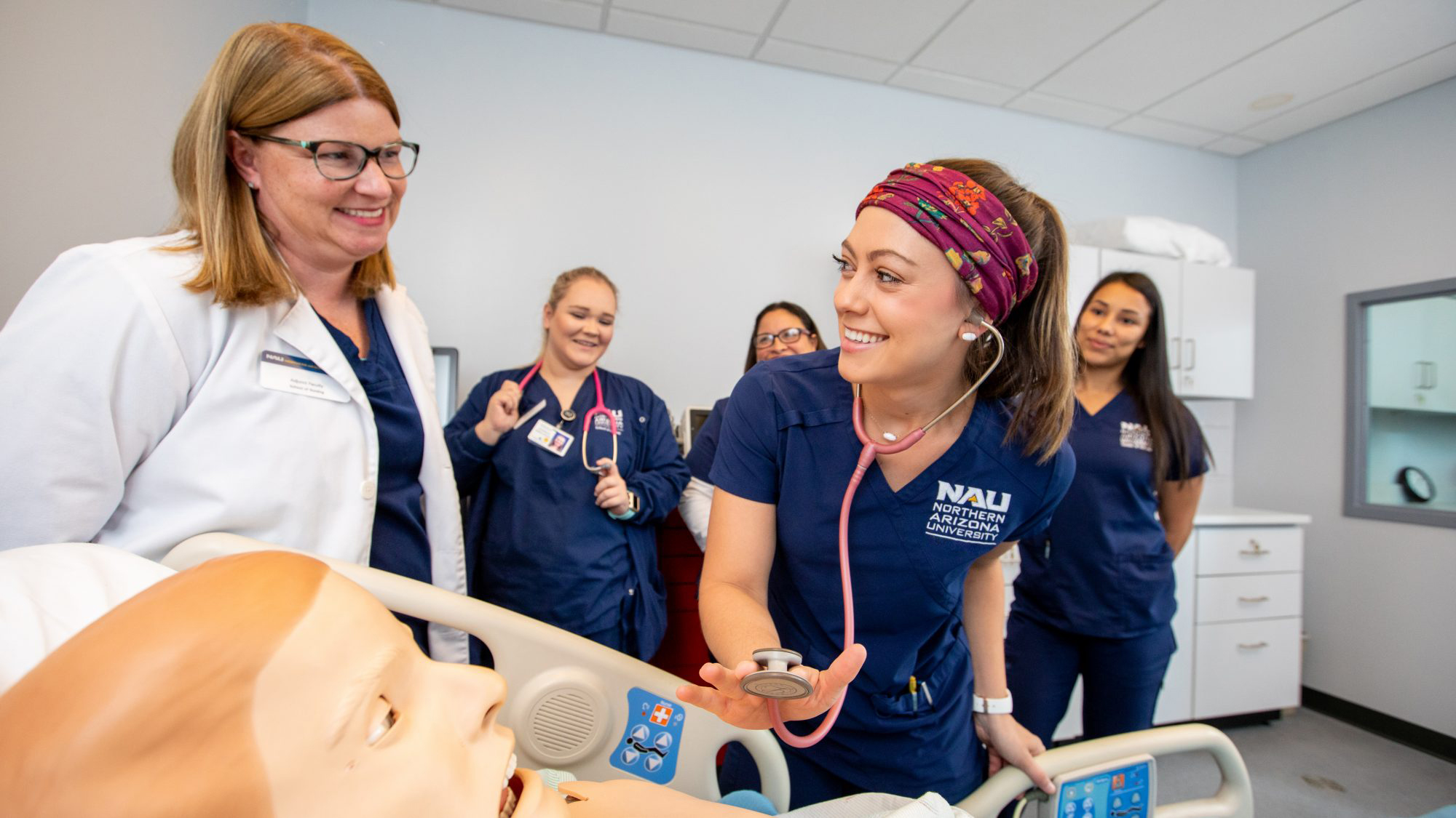 Student nurses working on dummy patient and smiling.