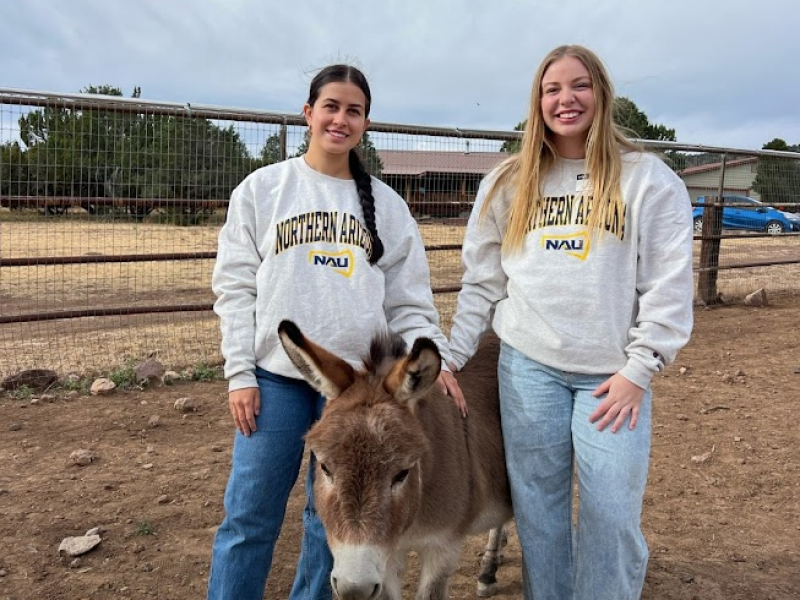 Two students posing with a small donkey.