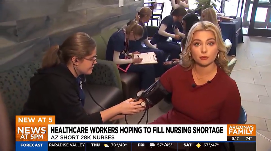 News image of news anchor getting her blood pressure checked by a NAU nursing student.