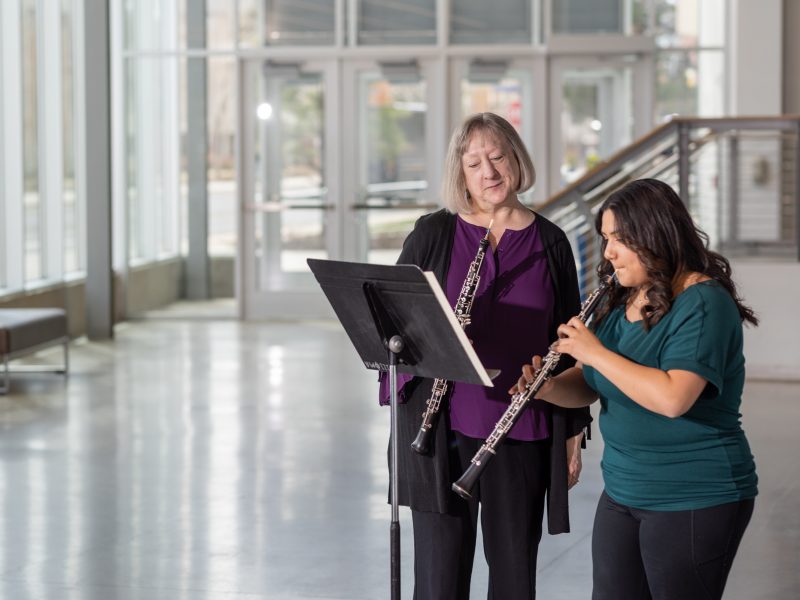 A student practicing the Oboe as their professor observes.