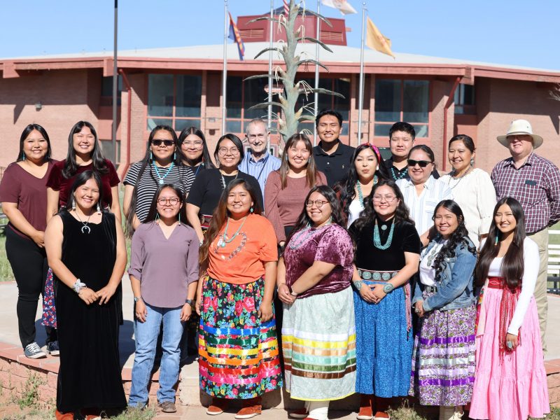Students standing in rows in front of a Din&eacute; College school building