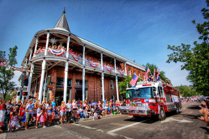 A flag cobered firetruck progresses through the parade