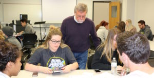 Professor Richard Lei looks on as students put finishing touches on their advertising plans for the Kia Soul. 