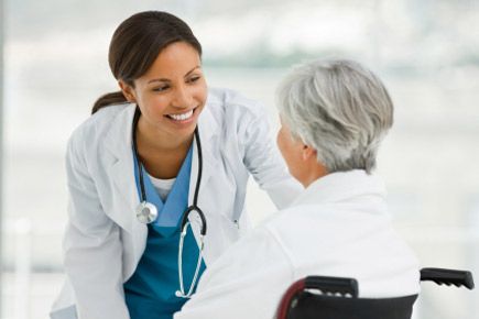 A nurse smiling to an elderly woman in her care