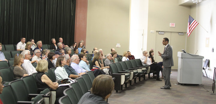 Frederick W. Gooding Jr. gestures while speaking in front of a seated crowd