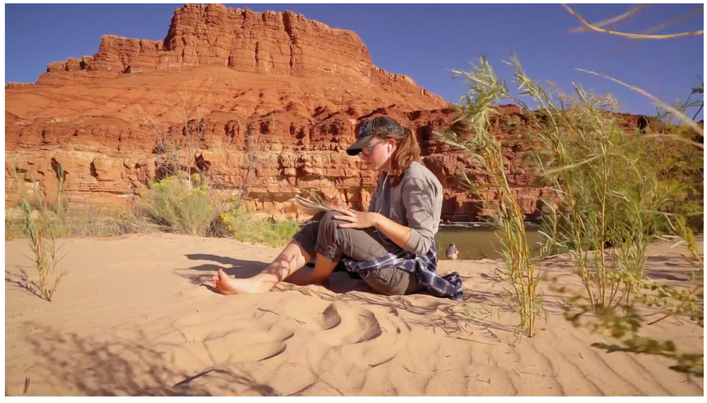 Girl sits in sand and paints