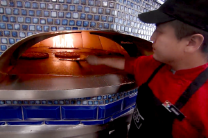 DuB worker prepares pizza in oven