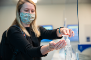 student putting hand sanitizer on