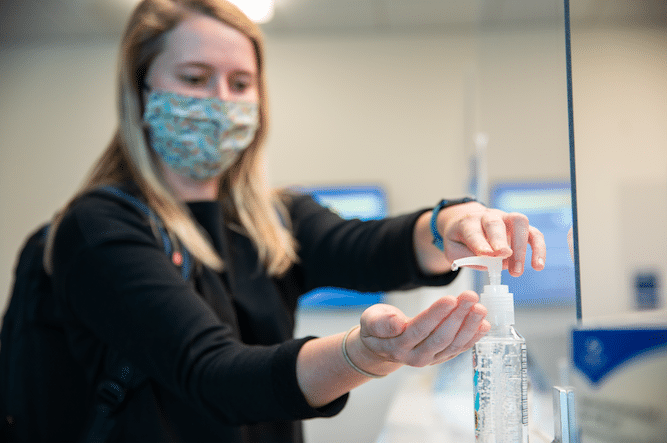 student putting hand sanitizer on