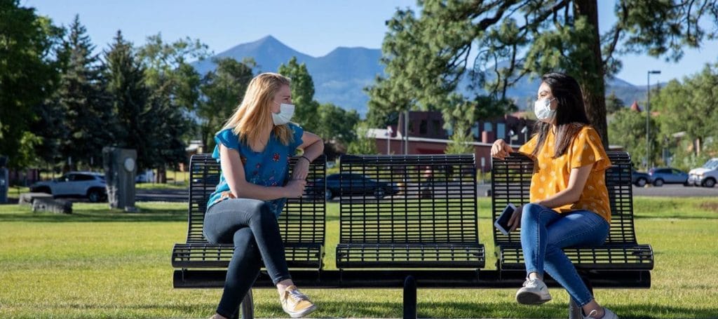 Masked students sit on bench