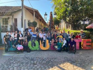 Large group photo in front of sign saying Quelite, the town where Acosta's family is from.