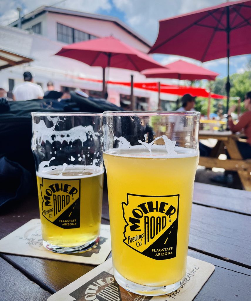 two pint glasses of beer on an outside patio table