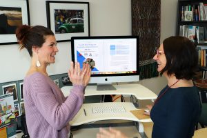 Kelly McCue and Samantha Sabo speak in front of a computer