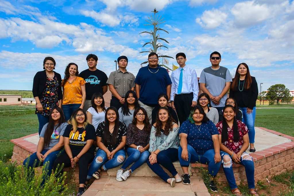 Group of students sitting in a field with blue sky