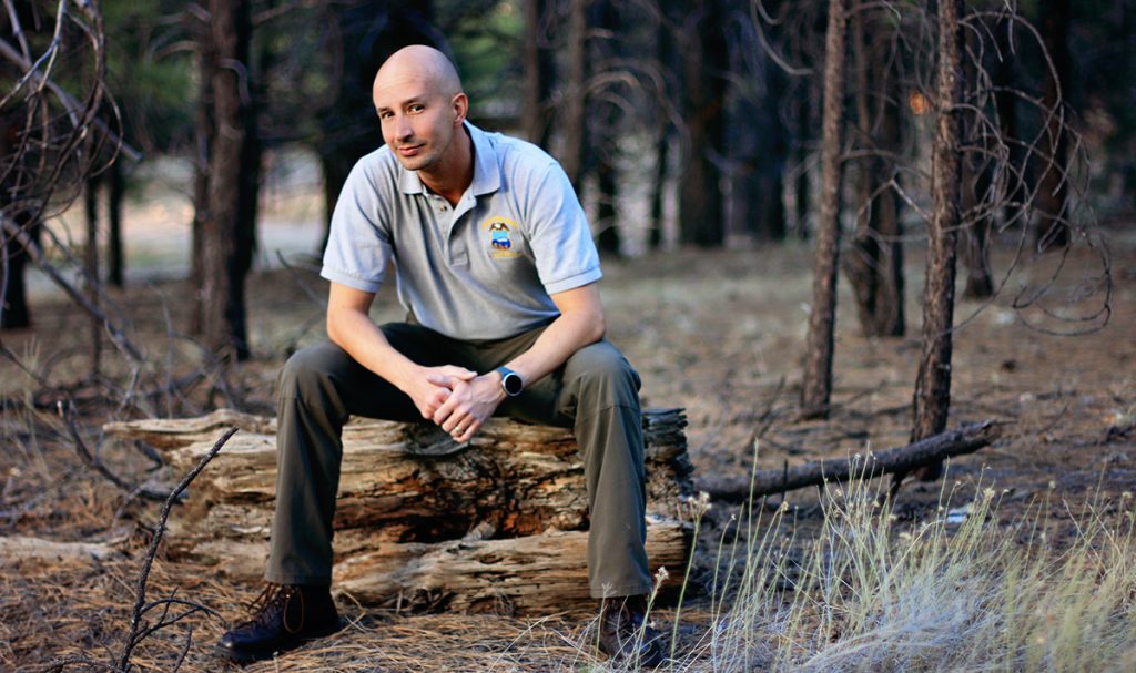 James Jensen sits on log