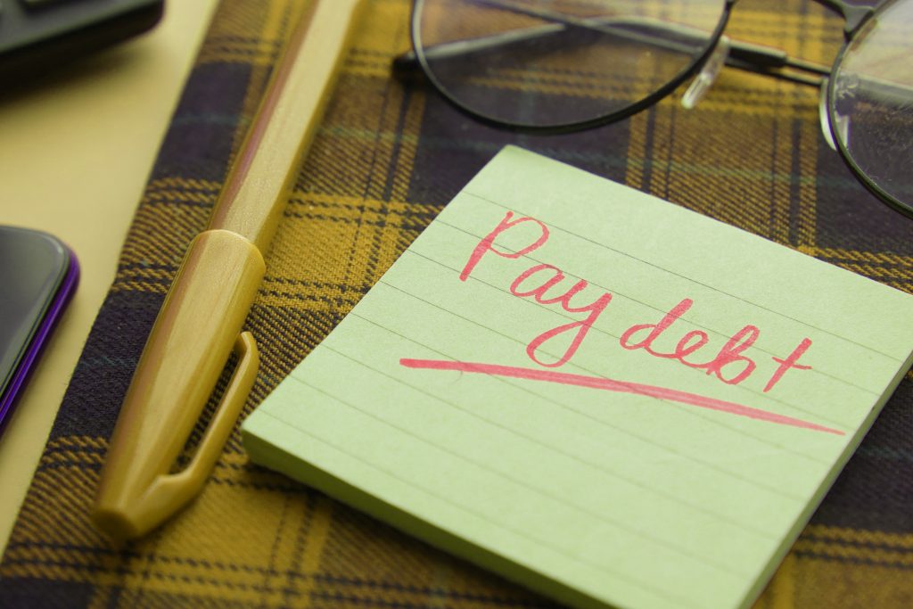 Sticky note that reads pay debt