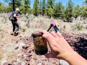Old jar held while students sift through trash