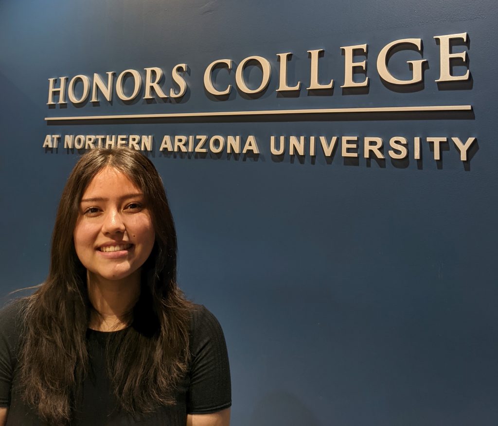 Olivia Konig standing in front of an Honors College sign