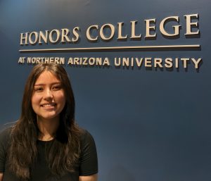 Olivia Konig standing in front of an Honors College sign