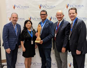 Five people in suits, including President Cruz Rivera holding a trophy