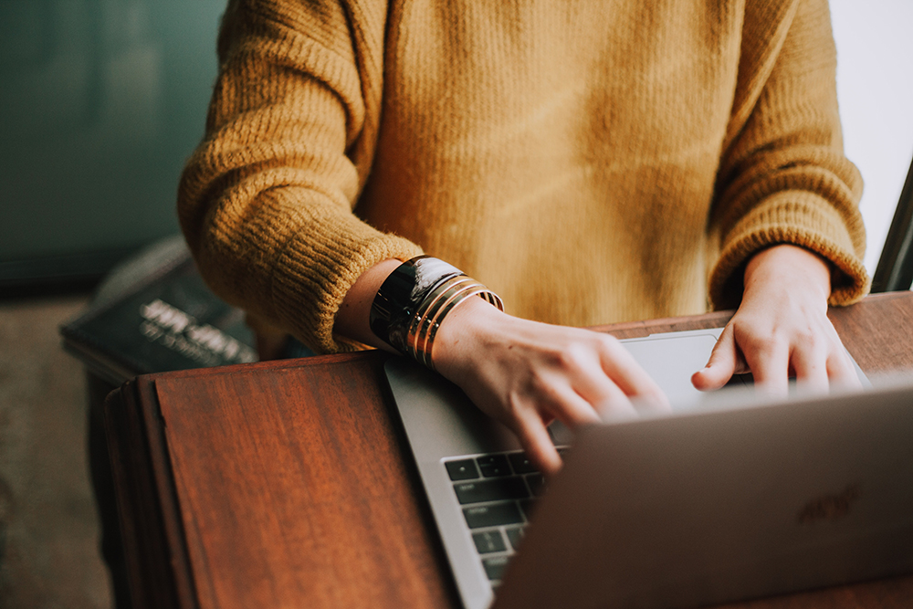 A person's hands typing on a laptop